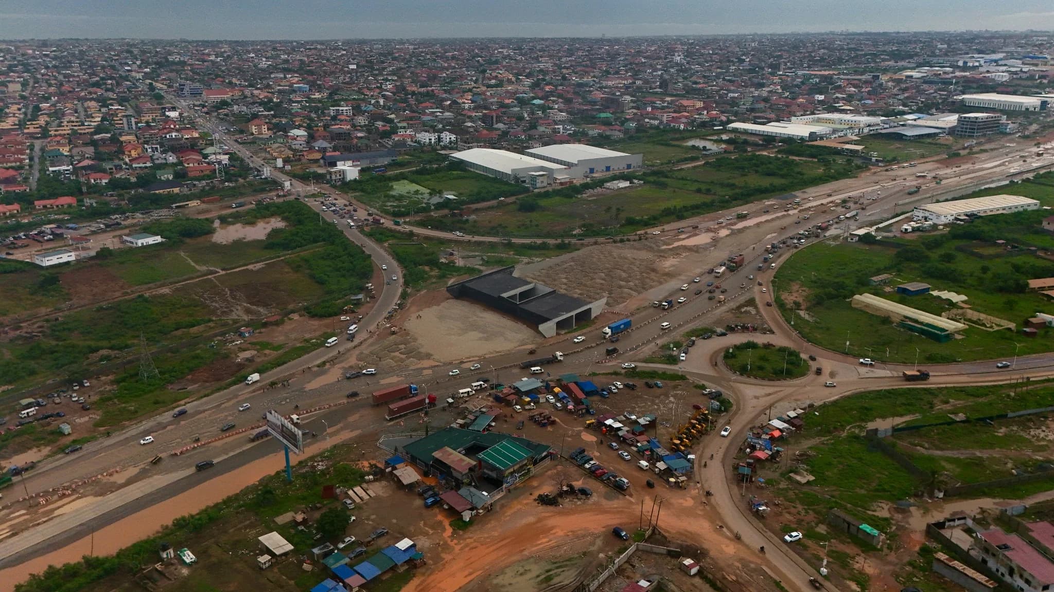 Aerial view of a major junction on the corridor, with a completed underpass portal, a roundabout and diverted traffic through a built-up area