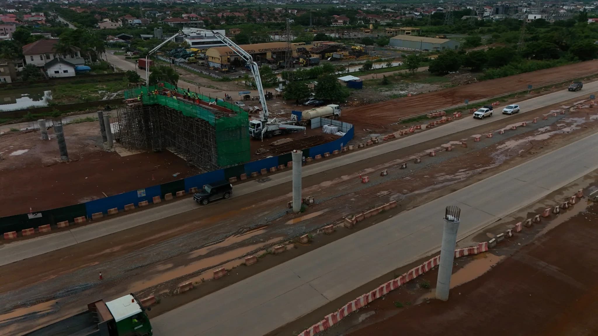 Aerial view of the corridor with newly cast bridge piers rising beside a completed concrete carriageway carrying traffic