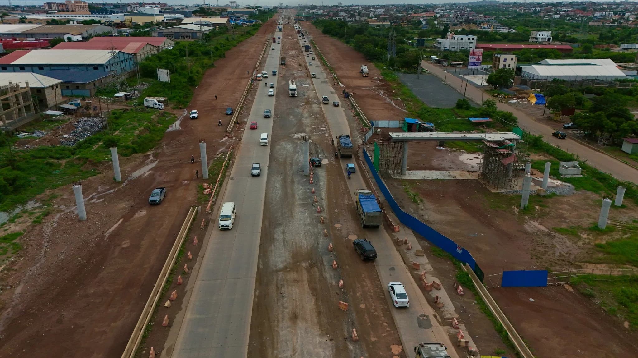 Wide aerial view along the corridor showing rows of new bridge piers and a partially completed concrete carriageway with traffic