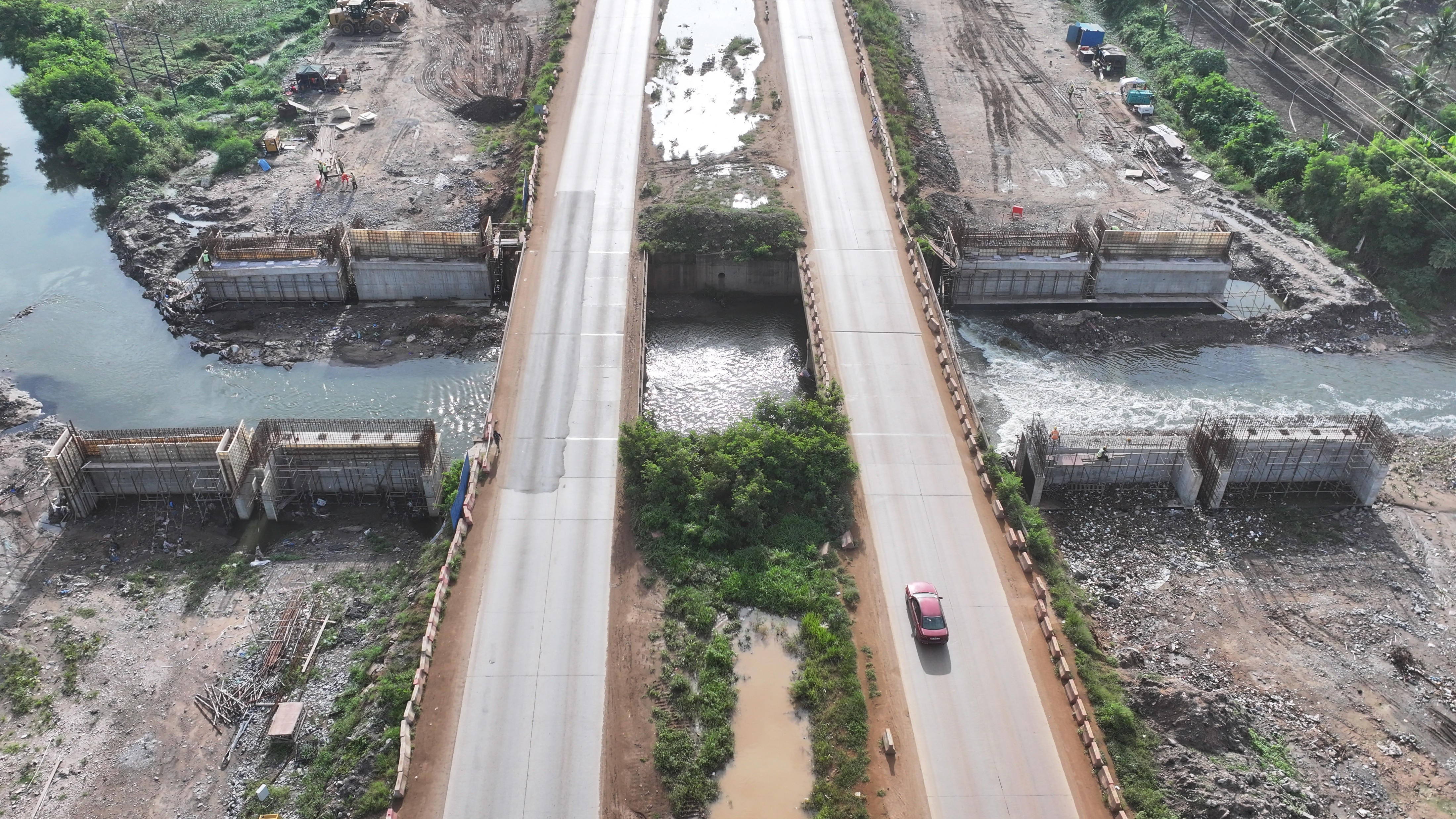 Aerial view of a river crossing with box and bridge culverts under construction on both sides of the road