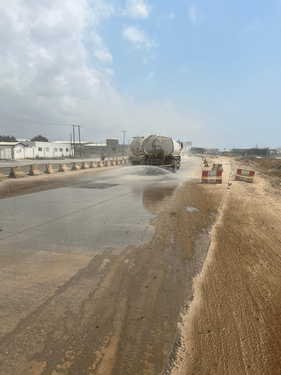 A water tanker spraying the road surface for dust suppression along the construction corridor