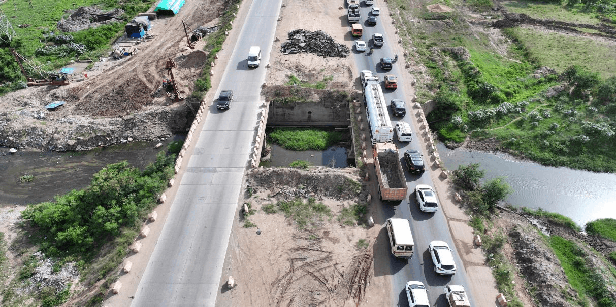 Aerial view of culvert works beneath a road crossing a watercourse, with queuing traffic