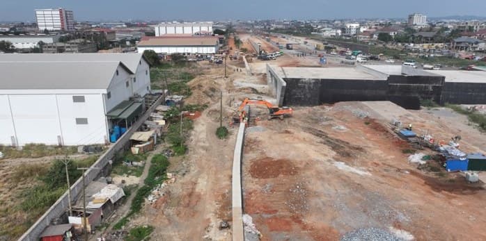 Footing wall construction on the right-hand side at Teshie Link Interchange, Km 6+380, with an excavator working alongside the corridor